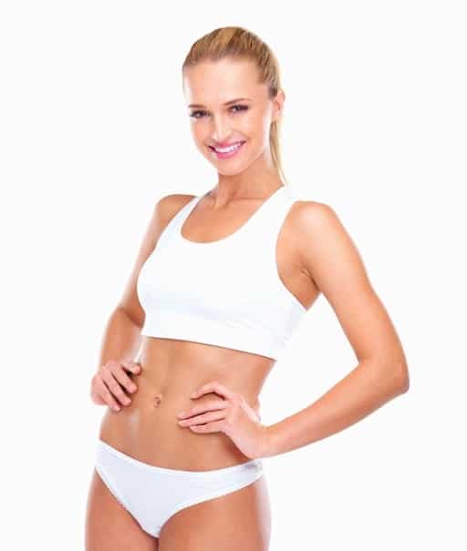 Portrait of attractive woman in sports bra smiling over white background